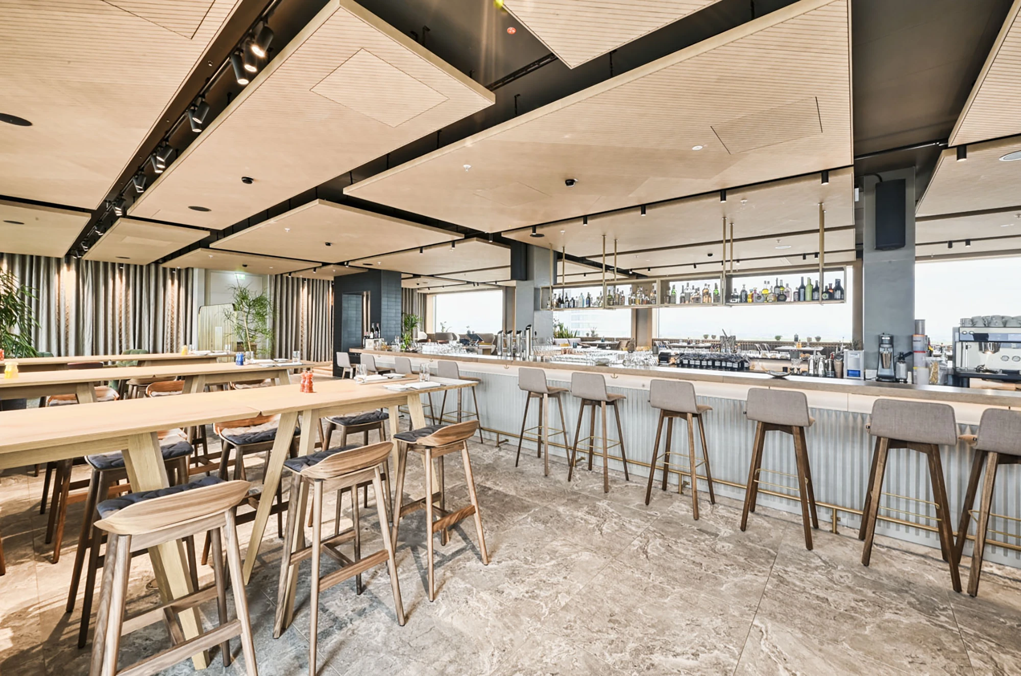 LIGNO® Akustikpaneele in Weißtanne verbessern die Raumakustik im Restaurantbereich– viele Leuchten betonen das helle, freundliche Raumgefühl.