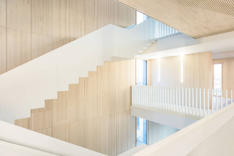 Die weiße Treppe im Bürogebäude der EWS hebt sich dynamisch von der hellen Wandverkleidung aus Weißtanne ab und wendet sich fast skulpturhaft durch das Treppenhaus. 