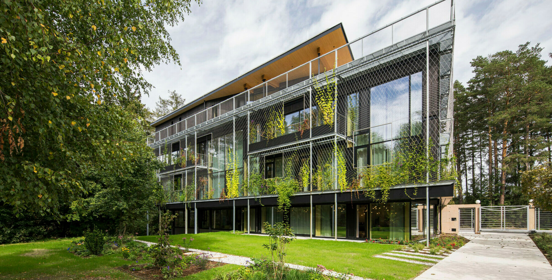 Die Fassade des ASI Firmensitzes wird geschmückt durch grüne Kletterpflanzen, die das Gebäude noch mehr als Teil der umgebenen Natur scheinen lassen. 