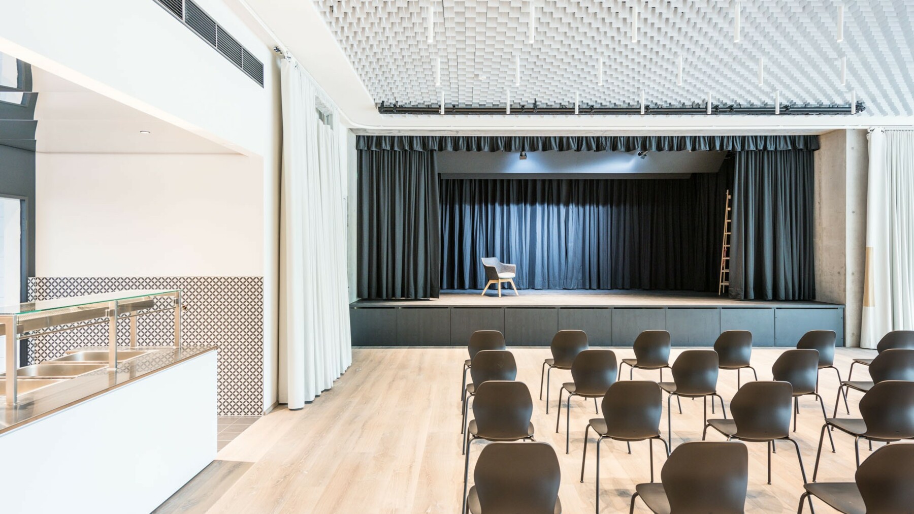Die im Bürogebäude integrierte Kulturhalle besteht unter anderem aus einer Bühne am Raumende und grenzt an die Kantine an. 