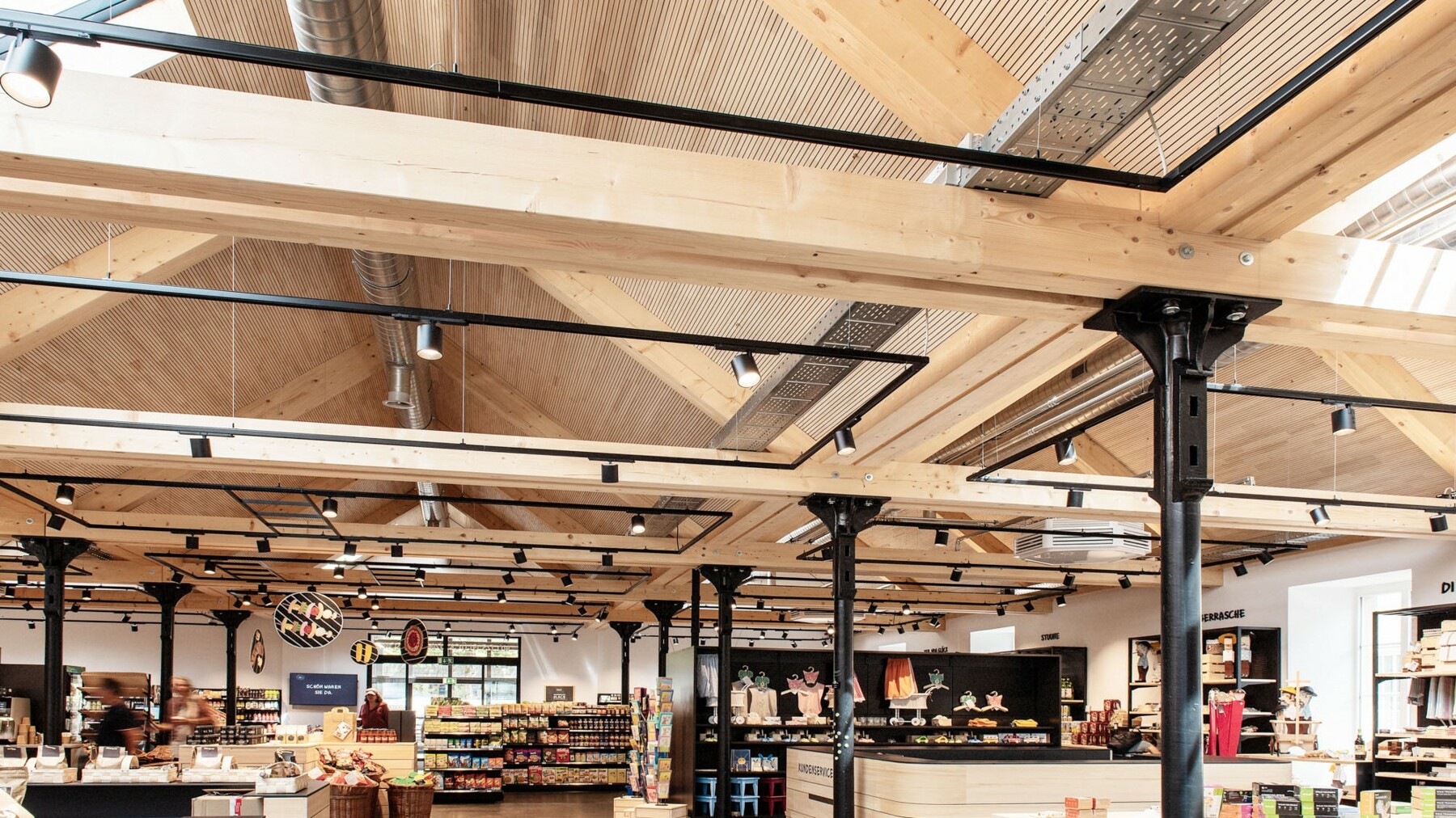 Für eine gute Akustik im Einkaufs-und Cafébereich sorgt die profilierte Unterseite der Dachbauteile LIGNO® Block Q3 mit integriertem Absorber. 