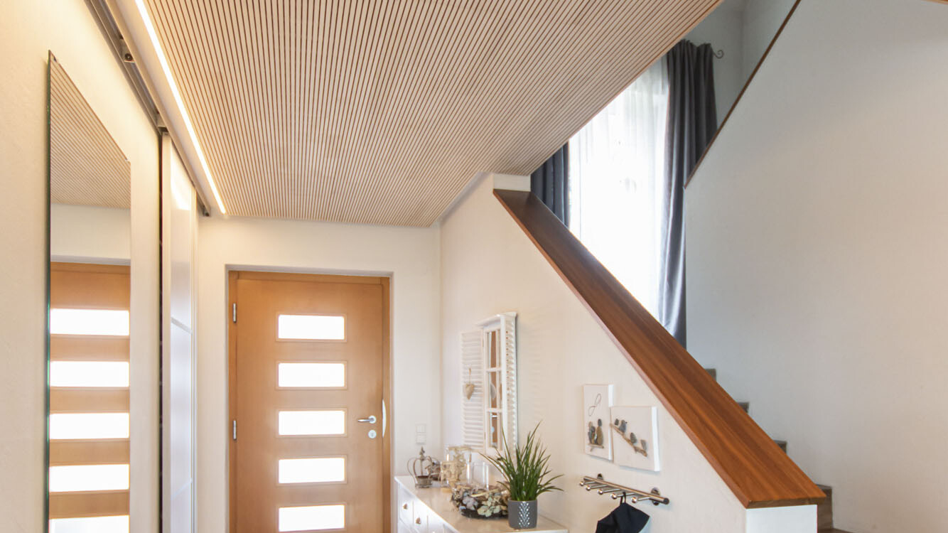 Die elegante Deckenverkleidung aus astreiner Weißtanne sorgt für eine optimale Raumakustik im Eingangsbereich. 