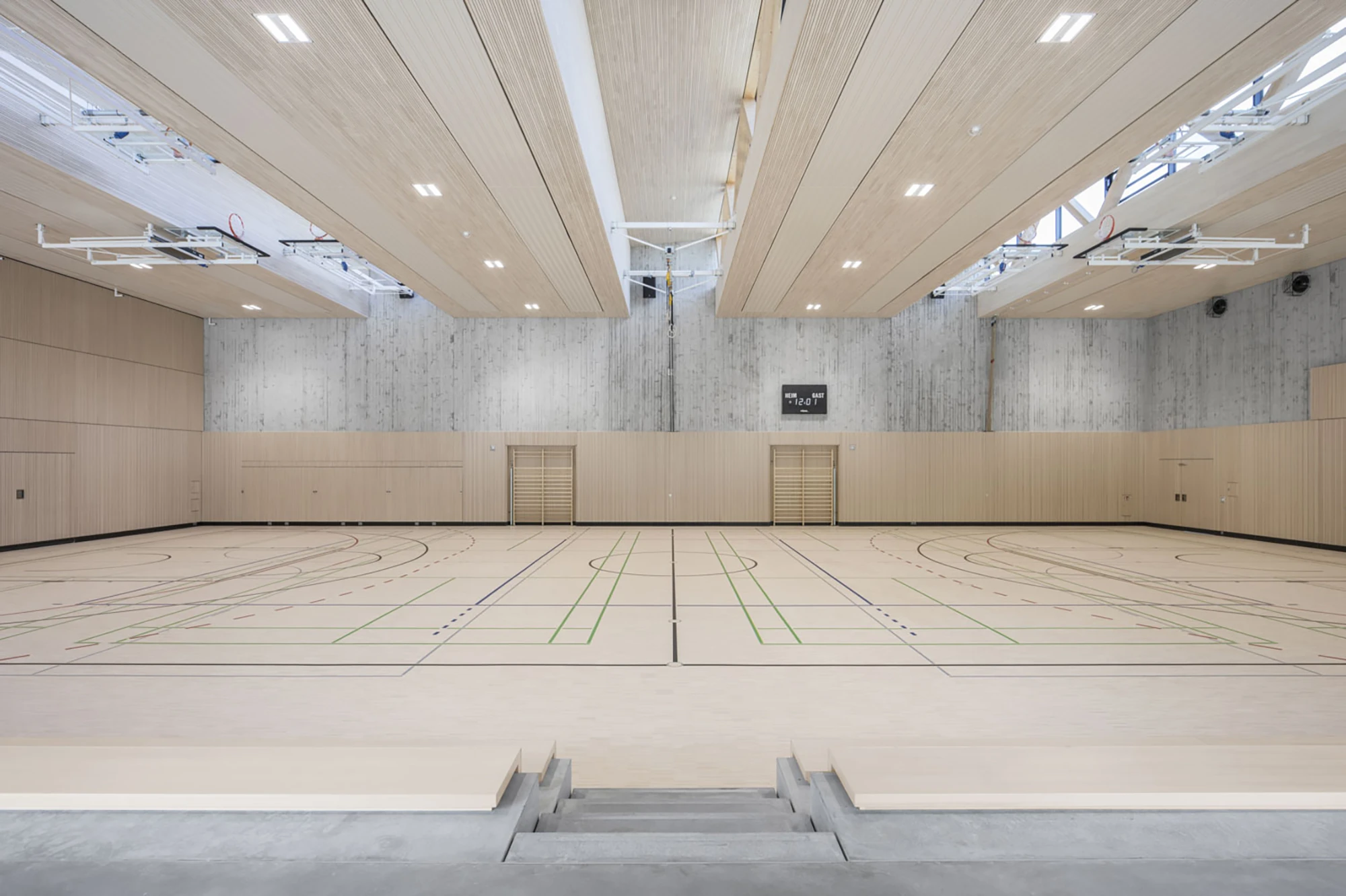 Die Decken der Halle wurden mit Akustikpaneelen in heller Weißtanne und die Wände ringsum mit LIGNO® Akustik Sport Prallwänden ausgestattet.