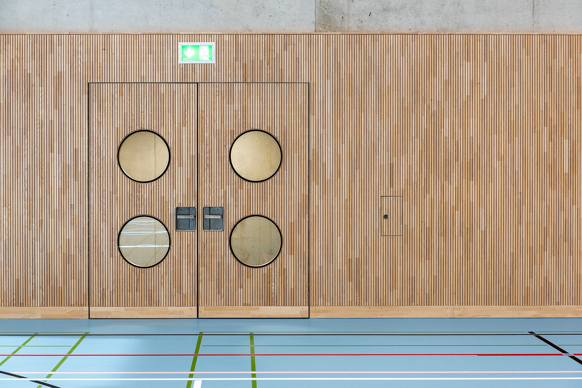 3-Feld-Sporthalle mit einer schallabsorbierenden Prallwand aus Echtholz.