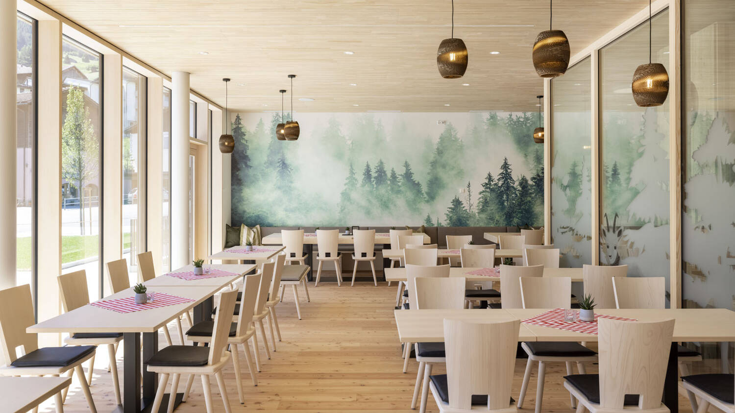 Die Wände des Speisesaals sind durch ein Waldprint geprägt, dass zusätzlich zu der Echtholzdecke aus Weißtanne ein Stück Natur ins Innere bringt. 