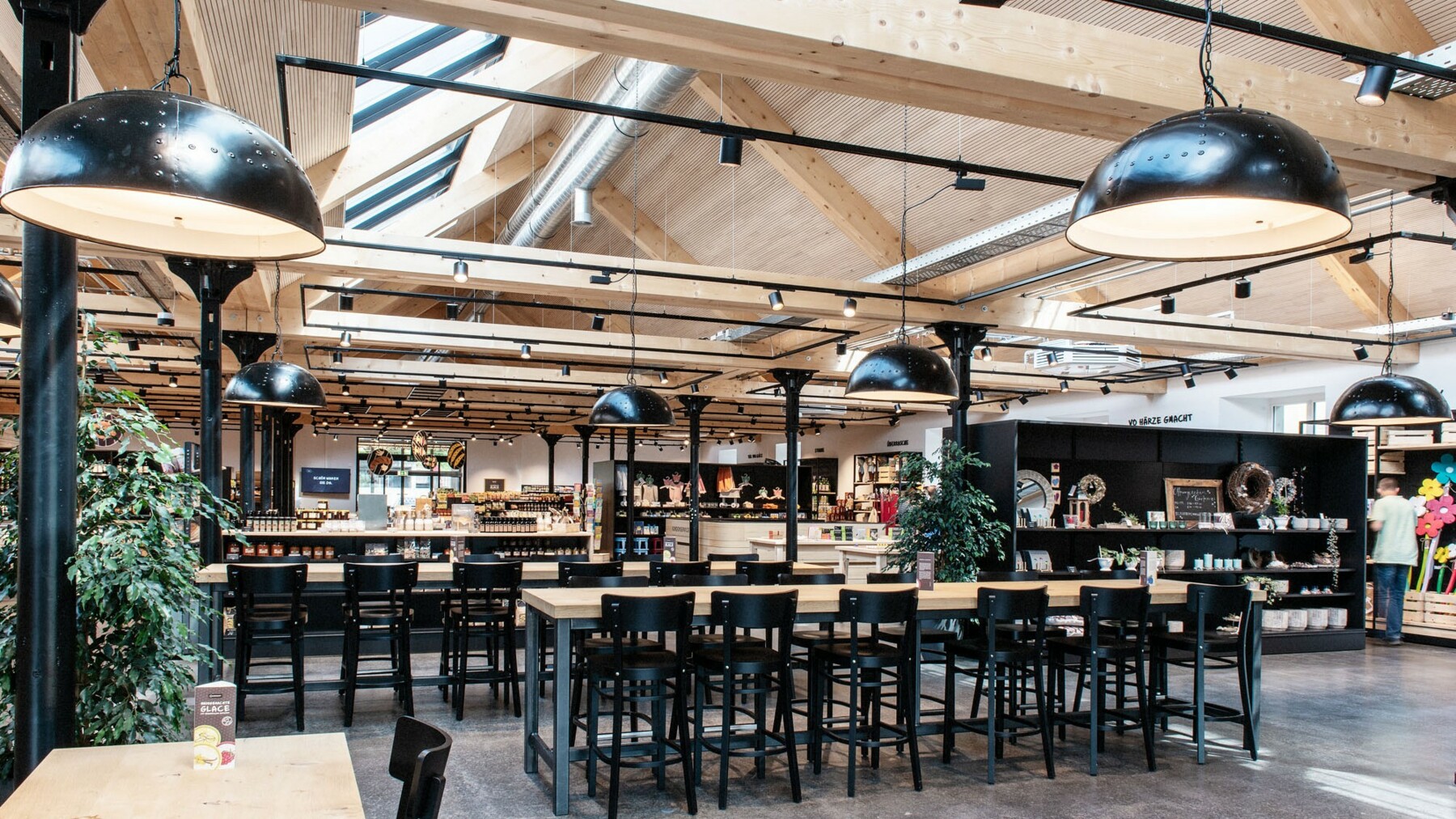 Das Café wird charakterisiert durch edle Metalloberflächen in Schwarz, die durch die Holzbalken in Weißtanne aufgelockert werden, die den Räumlichkeiten Wärme verleihen. 