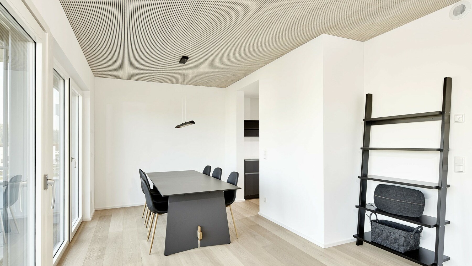 In der minimalistisch eingerichteten Wohnung mit dunklen Möbeln kommt die Deckensichtseite aus fein profilierter Weißtanne von Lignotrend besonders gut zur Geltung. 