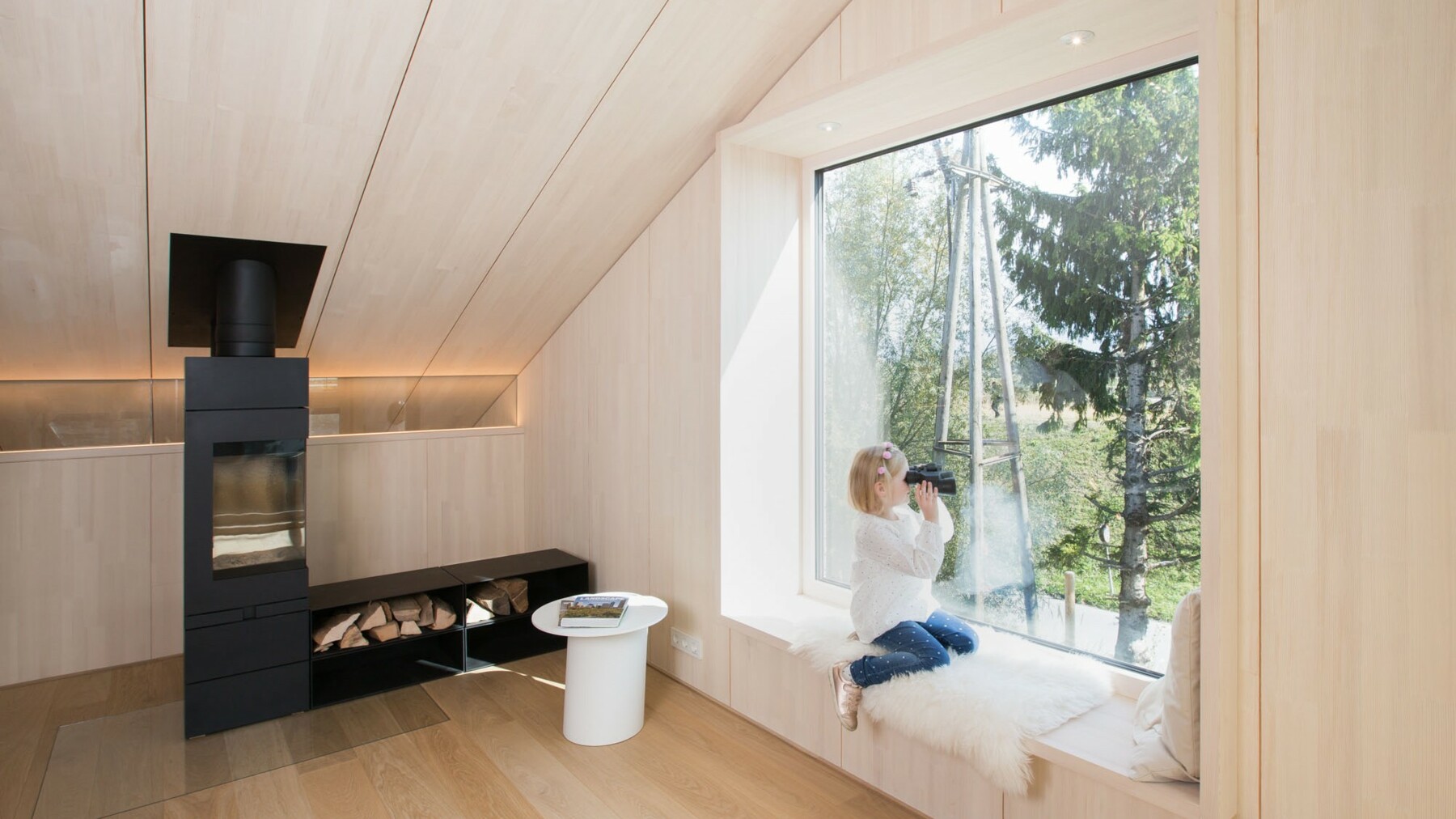 Die Sichtholzflächen aus Weißtanne werden im Wohnbereich durch ein Fenster in die Natur unterbrochen, das zum Sitzen und Rausschauen einlädt. 