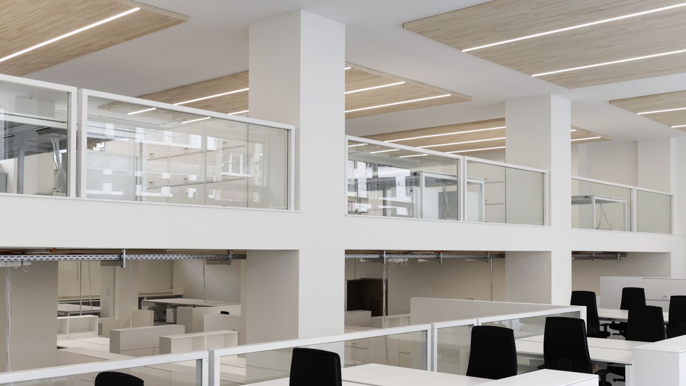 Die hellen, minimalistisch eingerichteten Büroräume sind geprägt von geraden Formen, in welchen die Decke in Weißtanne eine warme Komponente darstellt. 