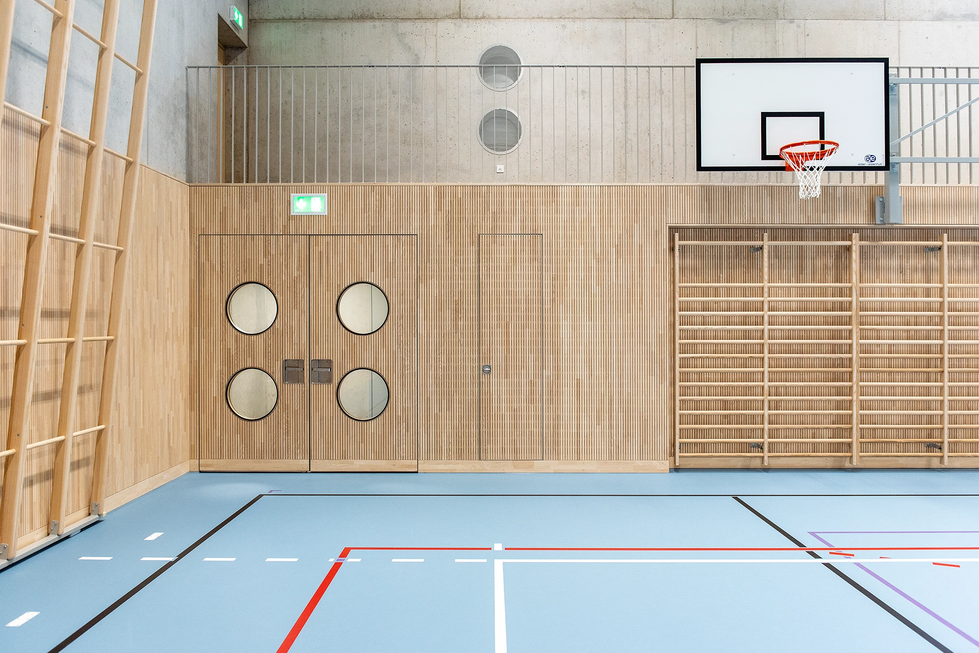 Anwendungsbeispiel für eine ballwurfsichere Prallwand mit Echtholz-Akustikpaneelen in einer 3-Feld-Sporthalle.