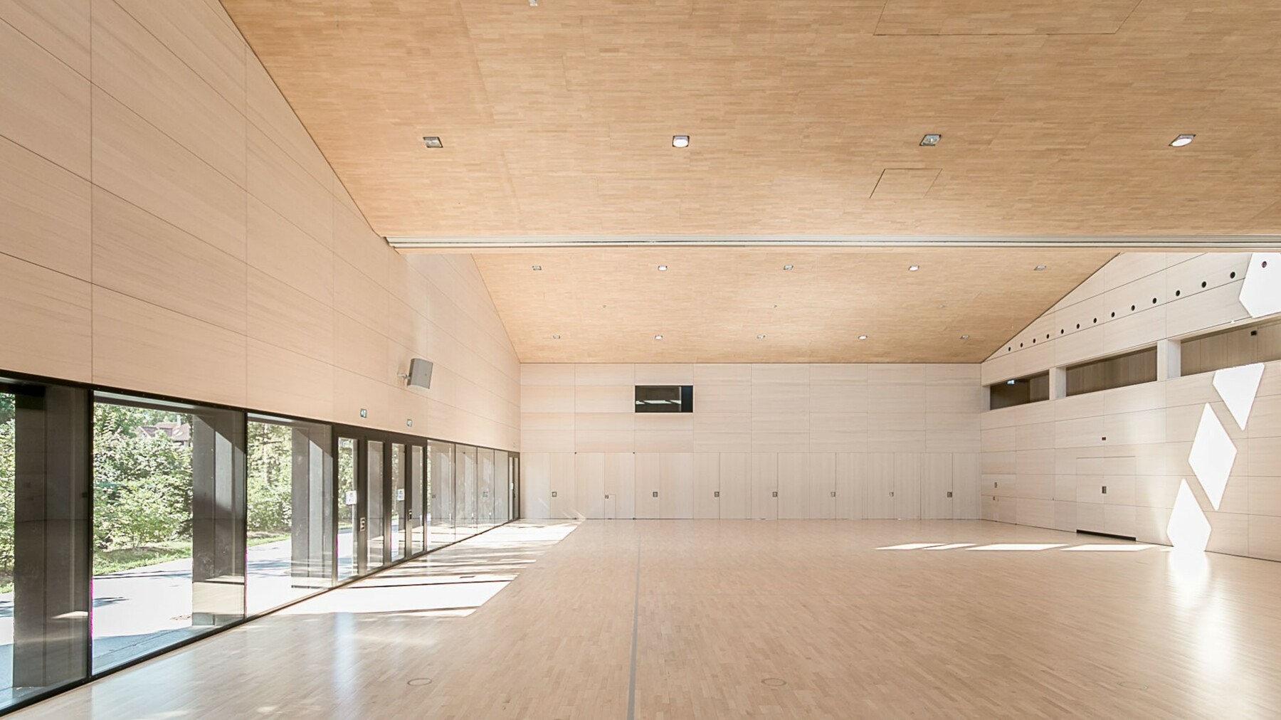 Die Echtholz Akustik-Deckenpaneele von Lignotrend verkleiden die gesamte Dachkonstruktion und verhüllen Lüftungstechnik und Installationsleitungen, sodass eine weite, einheitliche Fläche entsteht. 